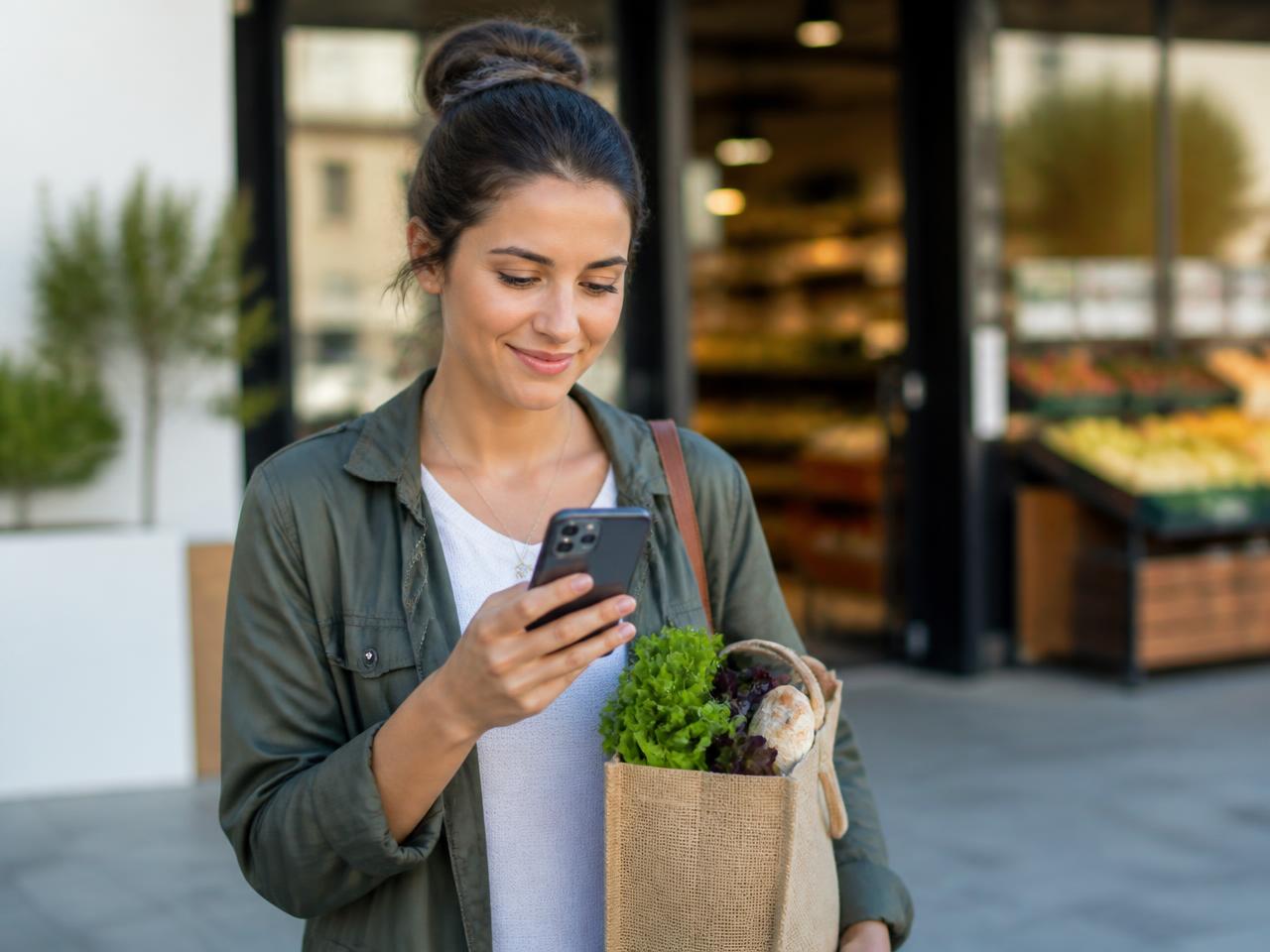 Local shopper scrolling on her mobile phone outside a grocery store